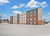 Thumbnail 20 of 30 - A large building with a mix of brick and panel siding is surrounded by a snowy field.