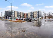 Thumbnail 28 of 31 - A parking lot in front of a multi-story apartment building.