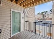 Thumbnail 7 of 22 - A balcony with a green door and a black railing.