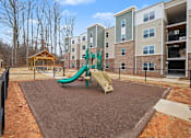 Thumbnail 2 of 22 - A playground with a green slide in front of apartment buildings.