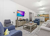 Thumbnail 13 of 66 - A living room with a blue couch and a flat screen TV mounted on the wall.