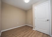 Thumbnail 14 of 58 - A room with a white door and wooden floor.