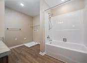 Thumbnail 18 of 58 - A white bathtub with a shower head and a white mat on the floor.