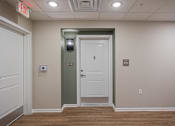 Thumbnail 21 of 58 - A white door with a green frame is in a room with a red exit sign above it.