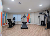 Thumbnail 37 of 58 - A gym with a treadmill, elliptical trainer, and a stationary bike.