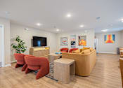 Thumbnail 40 of 58 - A living room with a red chair and a brown sofa.