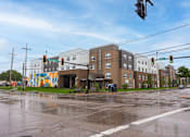 Thumbnail 50 of 58 - A wet street with a traffic light and a building with a mural on the side.