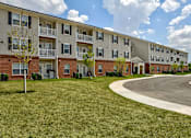 Thumbnail 49 of 56 - Apartment complex with a grassy area in front.