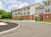 Thumbnail 52 of 56 - A large apartment complex with a parking lot in front.