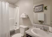Thumbnail 29 of 30 - A white bathroom with a toilet, sink, and shower.