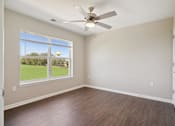 Thumbnail 30 of 38 - an empty living room with a ceiling fan and a window