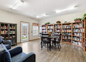 Thumbnail 16 of 66 - A room with a black table surrounded by black chairs and a bookshelf filled with books.