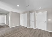 Thumbnail 8 of 18 - A room with white doors and a light brown floor.