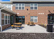 Thumbnail 14 of 38 - a patio with two picnic tables in front of a brick building