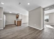 Thumbnail 11 of 18 - A spacious room with wooden flooring and a refrigerator in the corner.