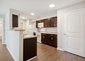 Thumbnail 29 of 38 - a white kitchen with dark cabinets and a white door