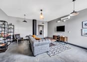 Thumbnail 23 of 51 - a living room with a gray couch and a tv on the wall