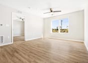 Thumbnail 7 of 26 - an empty living room with a ceiling fan and a window