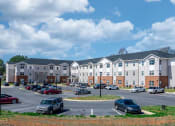 Thumbnail 2 of 22 - a parking lot with cars in front of an apartment building