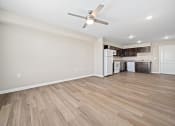 Thumbnail 14 of 35 - an empty living room with a ceiling fan and a kitchen
