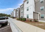 Thumbnail 28 of 50 - a row of apartment buildings with cars parked in front of them