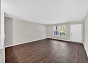 Thumbnail 27 of 51 - Empty room with wooden flooring and white walls.