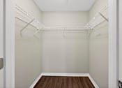 Thumbnail 30 of 51 - A walk-in closet with white shelving and a wooden floor.