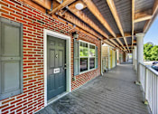 Thumbnail 46 of 51 - A long wooden porch with a brick wall and a door with the number 406 on it.