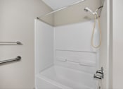 Thumbnail 30 of 48 - A white bathroom with a towel hanging on the shower rod.