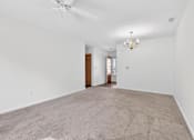 Thumbnail 33 of 49 - A spacious room with a carpeted floor and a chandelier hanging from the ceiling.