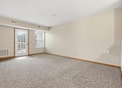 Thumbnail 29 of 66 - A large empty room with a carpeted floor and a door leading to a balcony.