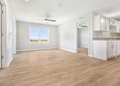 Thumbnail 15 of 26 - an empty living room with a kitchen and a ceiling fan