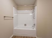 Thumbnail 6 of 58 - A white bathtub with a shower head and a towel bar.