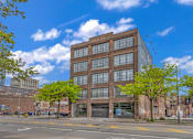 Thumbnail 12 of 51 - a six story brick and glass building on a city street with trees in front of it