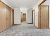 Thumbnail 33 of 66 - A hallway with wooden doors and carpeted flooring.
