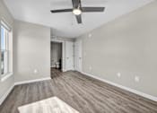 Thumbnail 15 of 18 - A room with a ceiling fan and wood flooring.