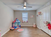 Thumbnail 36 of 50 - a bedroom with a ceiling fan and a door to a room with a play area