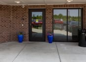 Thumbnail 2 of 26 - a building with two doors and two blue planters with purple flowers