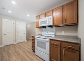 Thumbnail 16 of 48 - A kitchen with a white stove and wooden cabinets.