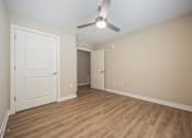 Thumbnail 9 of 48 - A room with a ceiling fan and light fixture, two doors, and a wooden floor.