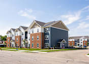 Thumbnail 5 of 48 - A large multi-story residential building with a parking lot in front.