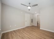Thumbnail 21 of 48 - A room with a ceiling fan and wooden flooring.