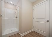 Thumbnail 44 of 48 - A white door is on the right of a bathroom with a walk in shower.
