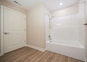 Thumbnail 40 of 48 - A white bathroom with a door and a bathtub.