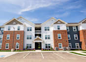 Thumbnail 29 of 48 - A large, modern apartment complex with a parking lot in front.