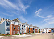 Thumbnail 28 of 48 - A row of modern apartment buildings with a clear blue sky above.