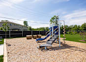 Thumbnail 26 of 48 - A playground with a blue slide and a brown gravel ground.