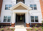 Thumbnail 30 of 48 - A white building with a covered walkway leading to the front door.