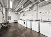 Thumbnail 33 of 51 - a row of washing machines in a room with a table and chairs