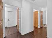 Thumbnail 49 of 49 - A hallway with white walls and wood floors with two doors on either side.